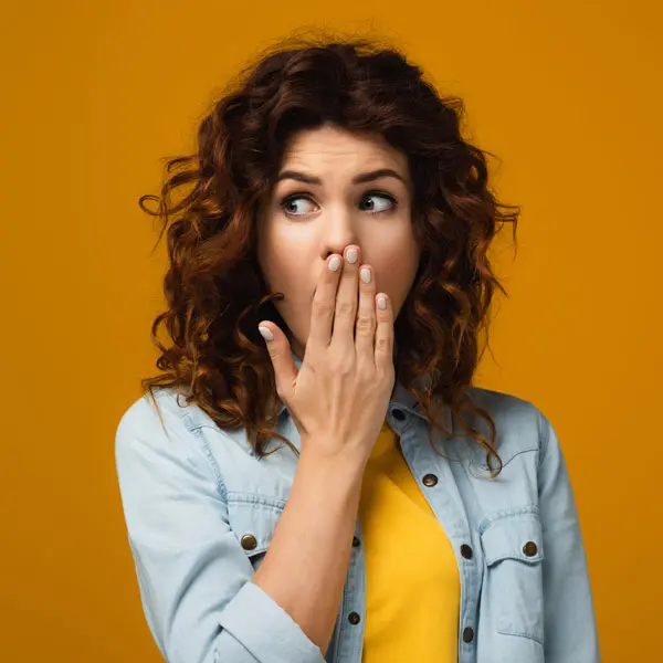 Woman with curly hair covering mouth
